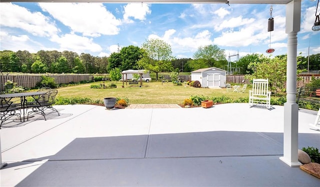 view of patio featuring a gazebo, fence, an outbuilding, and a storage shed