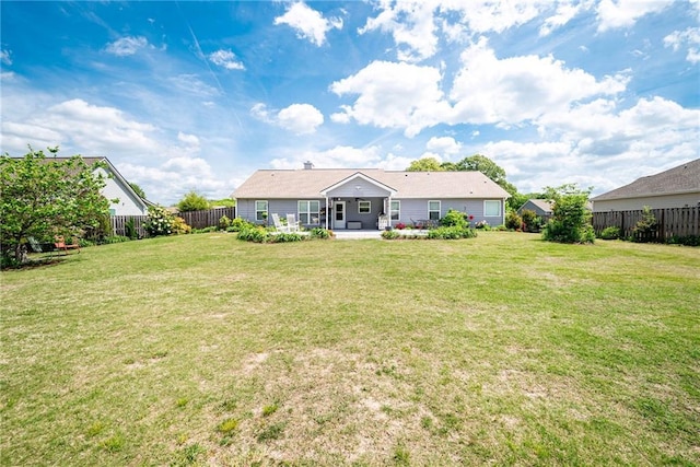 rear view of house with a fenced backyard, a yard, and a patio area