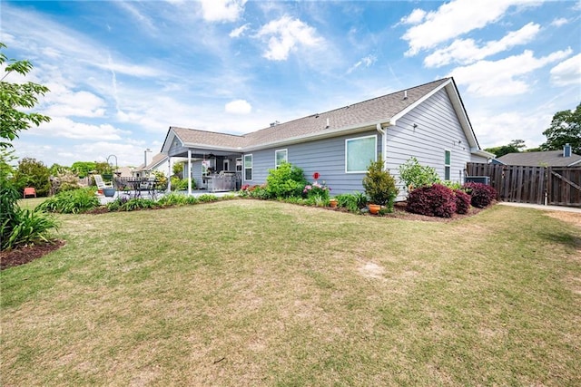 back of property featuring fence, a lawn, and a patio area