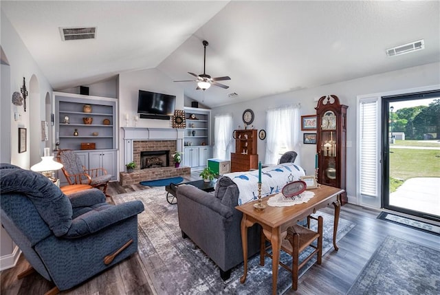living area with lofted ceiling, wood finished floors, visible vents, and a fireplace