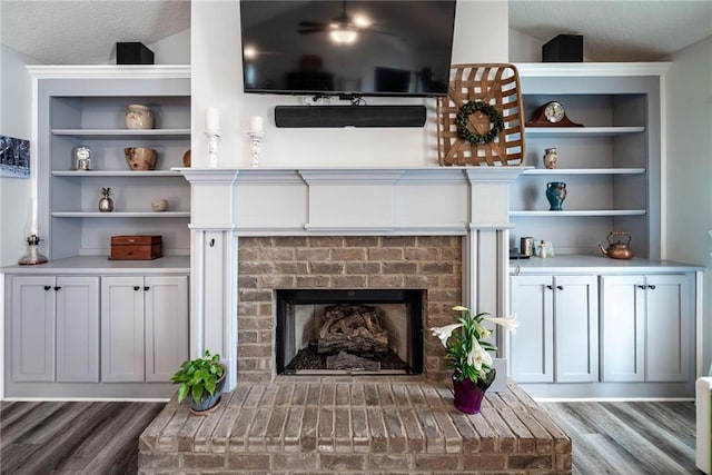 living room with a brick fireplace and wood finished floors
