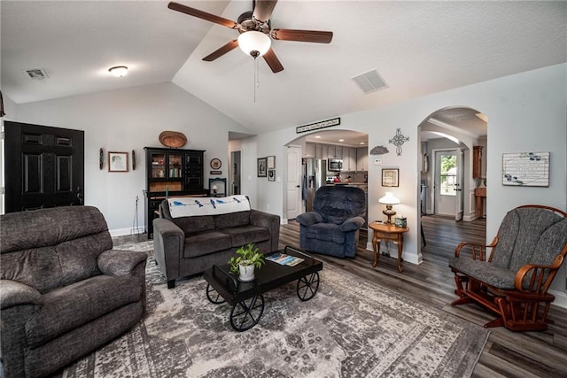 living area featuring ceiling fan, arched walkways, vaulted ceiling, and visible vents