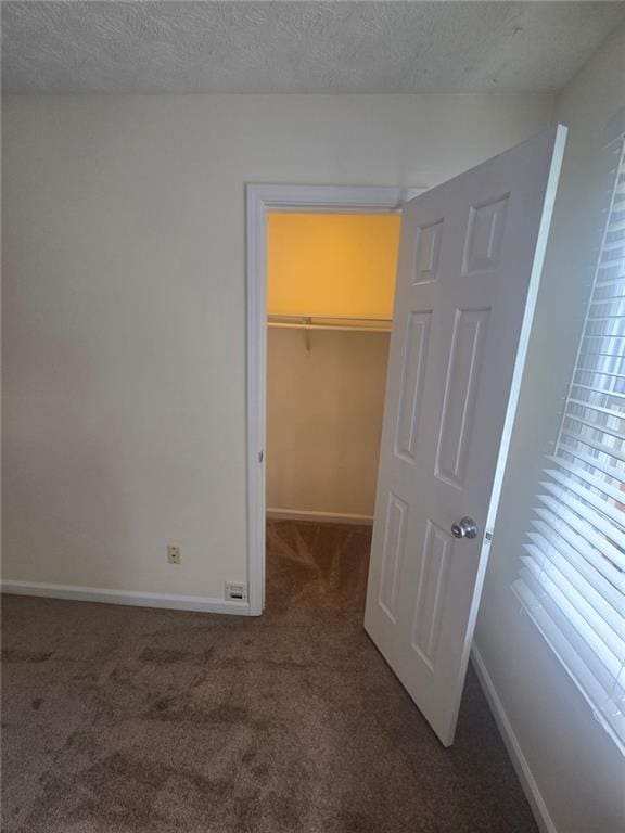 639 Royal Abbey Dr, Stone Mountain, GA 30088 - unfurnished bedroom with carpet flooring, a walk in closet, baseboards, a closet, and a textured ceiling
