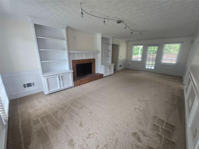 639 Royal Abbey Dr, Stone Mountain, GA 30088 - unfurnished living room featuring a decorative wall, built in shelves, a textured ceiling, carpet, and a fireplace
