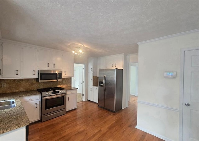 639 Royal Abbey Dr, Stone Mountain, GA 30088 - kitchen featuring appliances with stainless steel finishes, backsplash, white cabinetry, dark wood-style flooring, and a sink