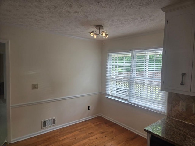 639 Royal Abbey Dr, Stone Mountain, GA 30088 - unfurnished dining area with light wood-type flooring, baseboards, and a textured ceiling