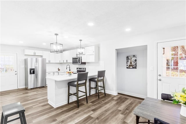 kitchen featuring appliances with stainless steel finishes, decorative light fixtures, white cabinetry, and a healthy amount of sunlight