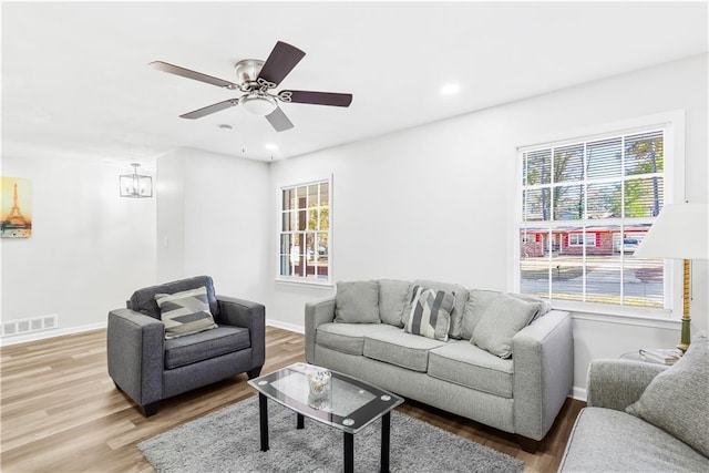 living room with hardwood / wood-style floors, ceiling fan with notable chandelier, and a wealth of natural light