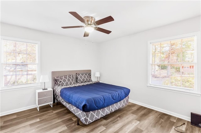 bedroom with wood-type flooring, multiple windows, and ceiling fan