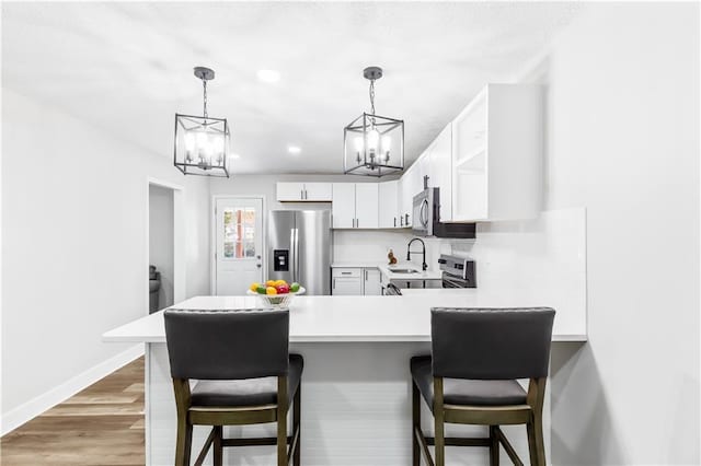 kitchen featuring kitchen peninsula, appliances with stainless steel finishes, dark hardwood / wood-style flooring, and white cabinetry