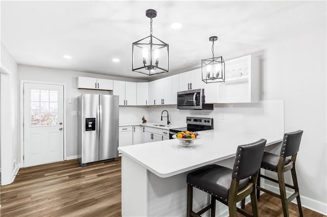 kitchen featuring sink, dark wood-type flooring, stainless steel appliances, decorative light fixtures, and white cabinets