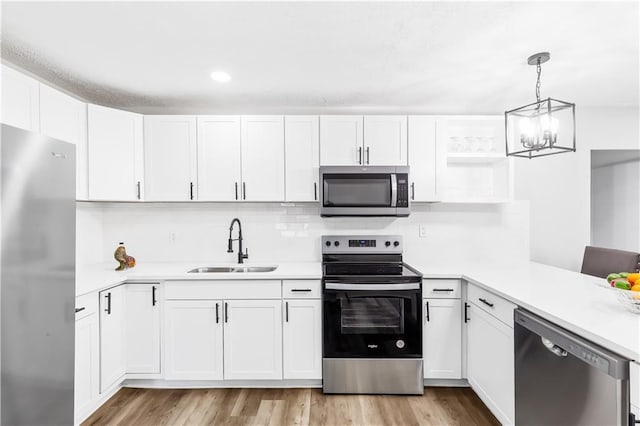 kitchen featuring stainless steel appliances, sink, light hardwood / wood-style flooring, white cabinetry, and hanging light fixtures