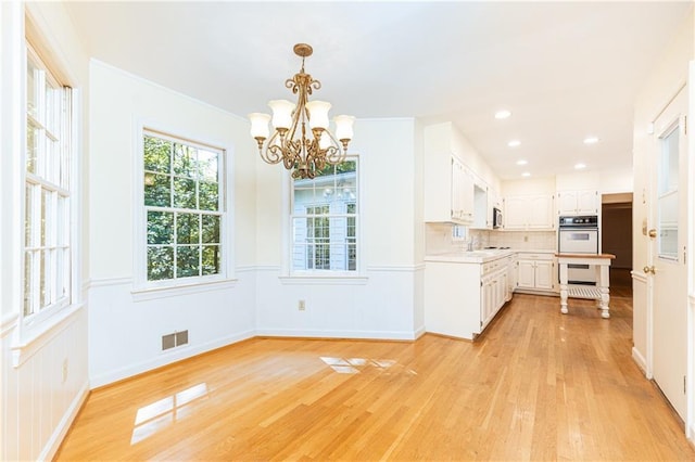 5287 Vernon Lake Dr, Atlanta, GA 30338 - kitchen with light countertops, double oven, light wood-style flooring, white cabinets, and a chandelier