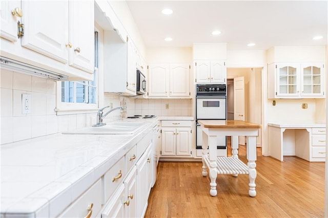 5287 Vernon Lake Dr, Atlanta, GA 30338 - kitchen featuring white double oven, white cabinetry, a sink, stainless steel microwave, and backsplash