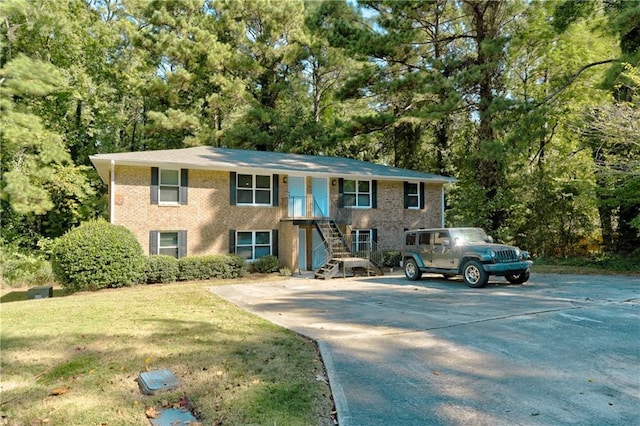 view of front of property with concrete driveway, brick siding, and a front yard