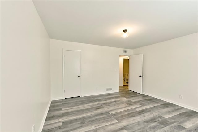 unfurnished room featuring visible vents, baseboards, and wood finished floors