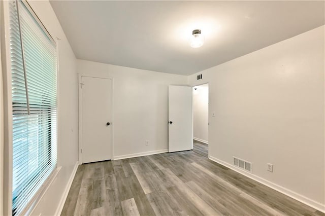 unfurnished bedroom featuring wood finished floors, visible vents, and baseboards