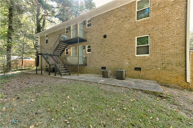 rear view of property featuring crawl space, brick siding, stairs, and a patio