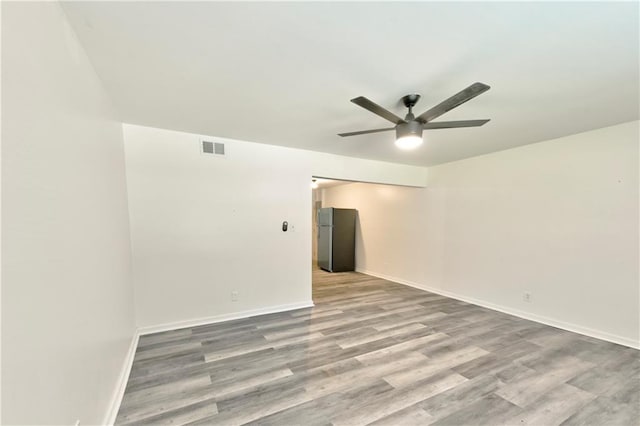 spare room with baseboards, visible vents, ceiling fan, and wood finished floors