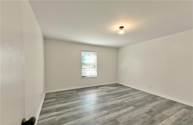 unfurnished room with baseboards and wood finished floors