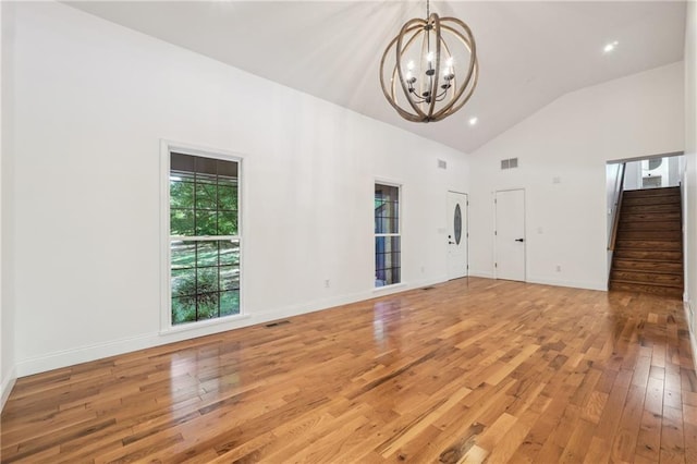 unfurnished living room featuring high vaulted ceiling, a notable chandelier, and light wood-type flooring