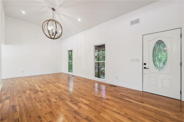 entrance foyer with an inviting chandelier, lofted ceiling, and wood-type flooring