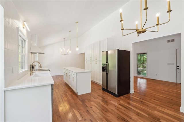 kitchen featuring stainless steel refrigerator with ice dispenser, sink, a notable chandelier, pendant lighting, and white cabinets