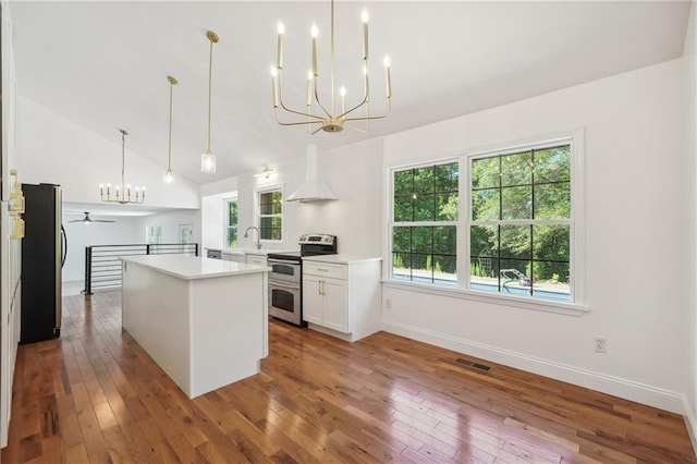 kitchen with white cabinetry, decorative light fixtures, wall chimney exhaust hood, and appliances with stainless steel finishes