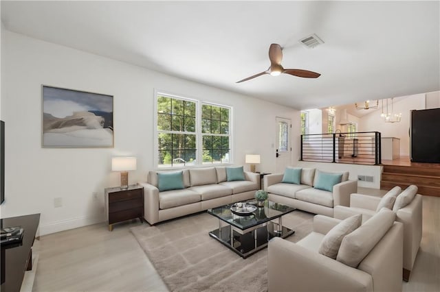 living room featuring ceiling fan with notable chandelier and light hardwood / wood-style floors