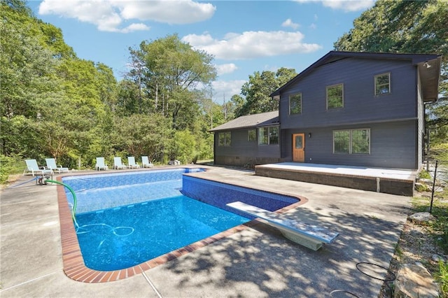 view of pool with a patio and a diving board