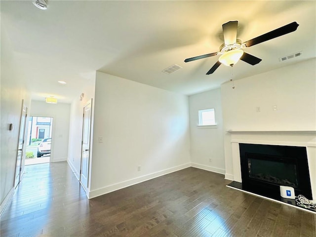 unfurnished living room with dark wood-type flooring, a fireplace, baseboards, and a ceiling fan