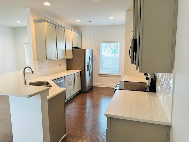 kitchen featuring a sink, range with electric stovetop, a peninsula, stainless steel refrigerator with ice dispenser, and decorative backsplash