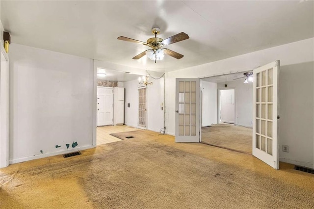 empty room featuring french doors, carpet, and ceiling fan with notable chandelier