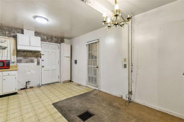 kitchen featuring visible vents, a notable chandelier, white cabinetry, baseboards, and light floors