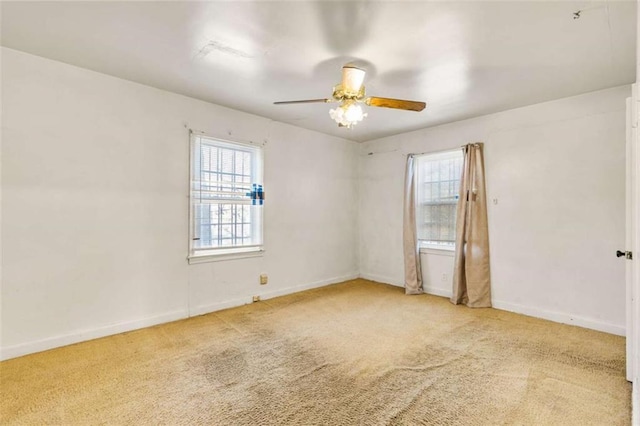 carpeted spare room featuring baseboards and ceiling fan