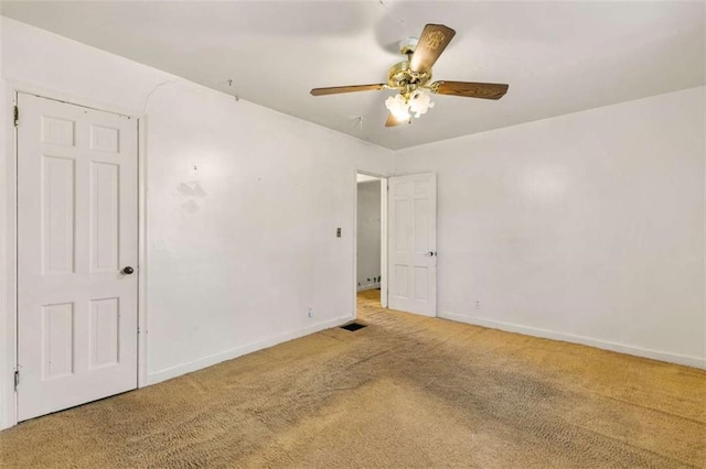 carpeted spare room with baseboards and a ceiling fan