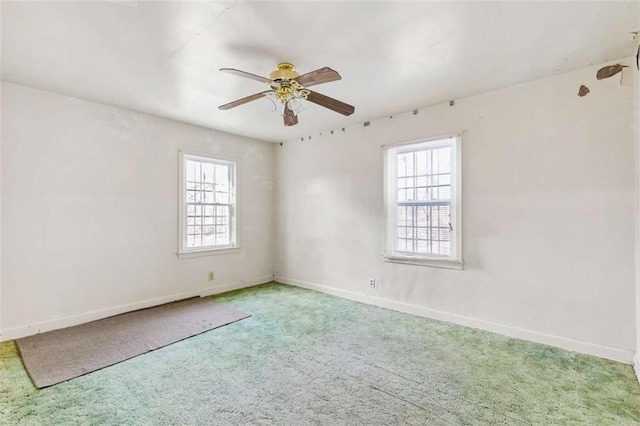 carpeted spare room with a healthy amount of sunlight, baseboards, and ceiling fan