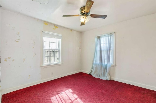 carpeted spare room with a healthy amount of sunlight, baseboards, and ceiling fan