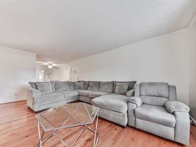 living area featuring light wood-style floors, a ceiling fan, and a textured ceiling