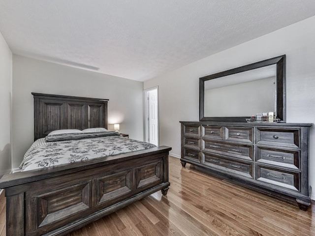 bedroom featuring a textured ceiling, wood finished floors, and baseboards