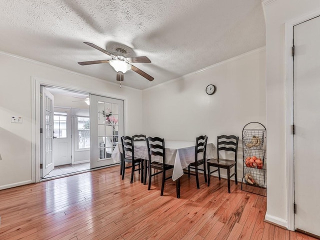 dining area with baseboards, a ceiling fan, wood-type flooring, ornamental molding, and a textured ceiling