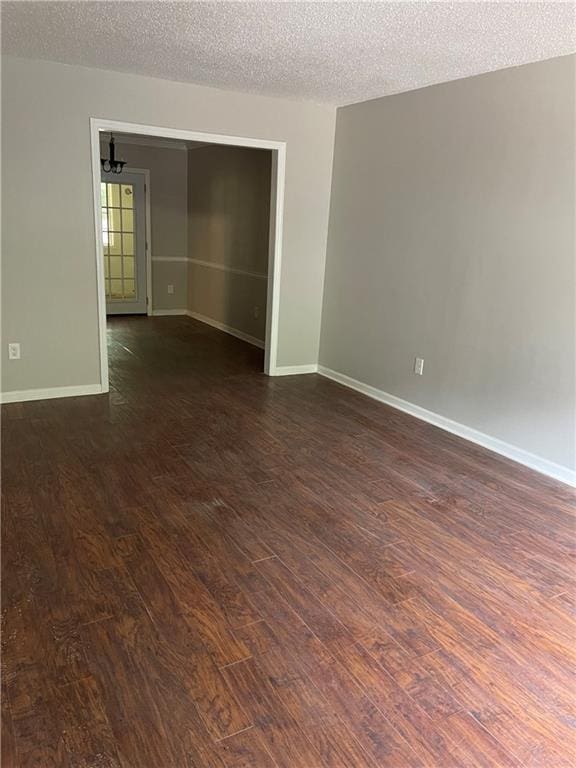 empty room with dark hardwood / wood-style floors and a textured ceiling