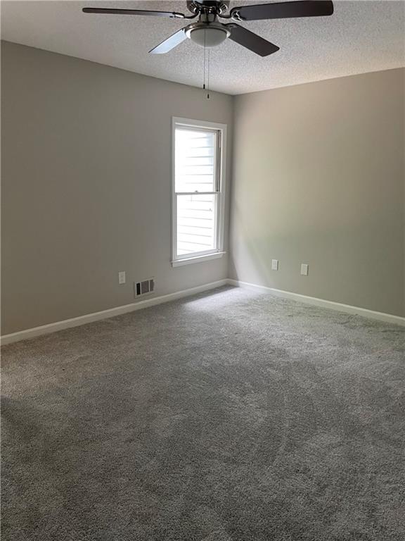 spare room featuring a textured ceiling, ceiling fan, and carpet