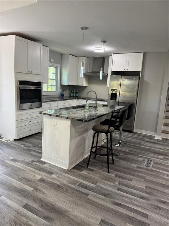 1382 Bennett Rd, Grayson, GA 30017 - kitchen with stainless steel appliances, wall chimney exhaust hood, dark wood-type flooring, a center island with sink, and white cabinetry