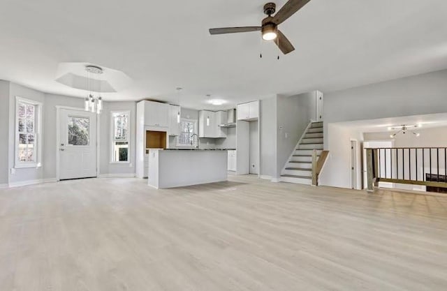 1382 Bennett Rd, Grayson, GA 30017 - unfurnished living room featuring a ceiling fan, a chandelier, light wood-style flooring, and baseboards