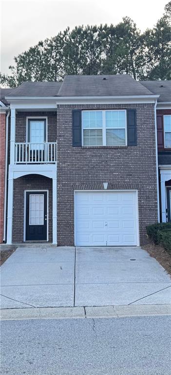 view of front of house featuring brick siding, a balcony, driveway, and a garage