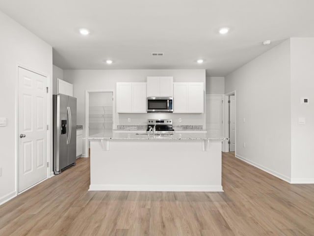 885 Lost Creek Blvd, Dallas, GA 30132 - kitchen with appliances with stainless steel finishes, recessed lighting, light wood-style floors, white cabinetry, and a kitchen island with sink