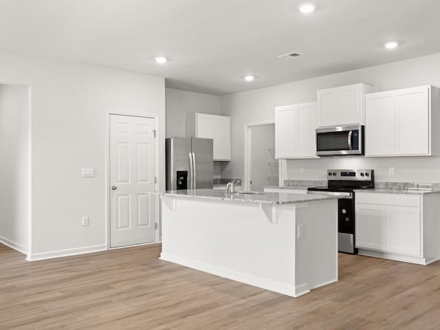 885 Lost Creek Blvd, Dallas, GA 30132 - kitchen with stainless steel appliances, an island with sink, white cabinetry, light wood-type flooring, and light stone countertops