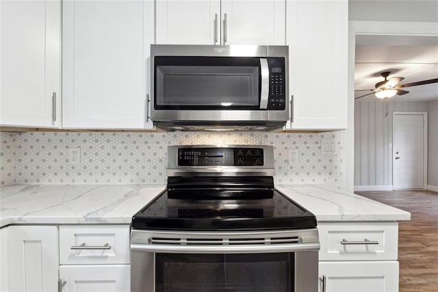 kitchen with appliances with stainless steel finishes, white cabinetry, decorative backsplash, and light stone counters