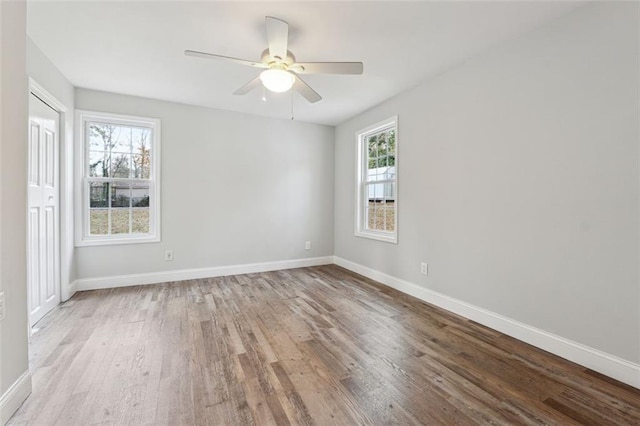 unfurnished room featuring ceiling fan, light wood-style floors, a wealth of natural light, and baseboards